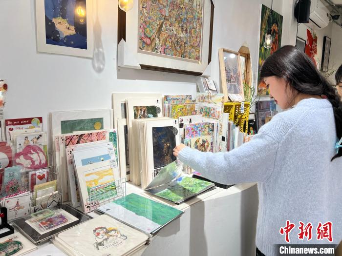 圖為藝術(shù)品商店內(nèi)，顧客挑選插畫作品?！＄婌?攝
