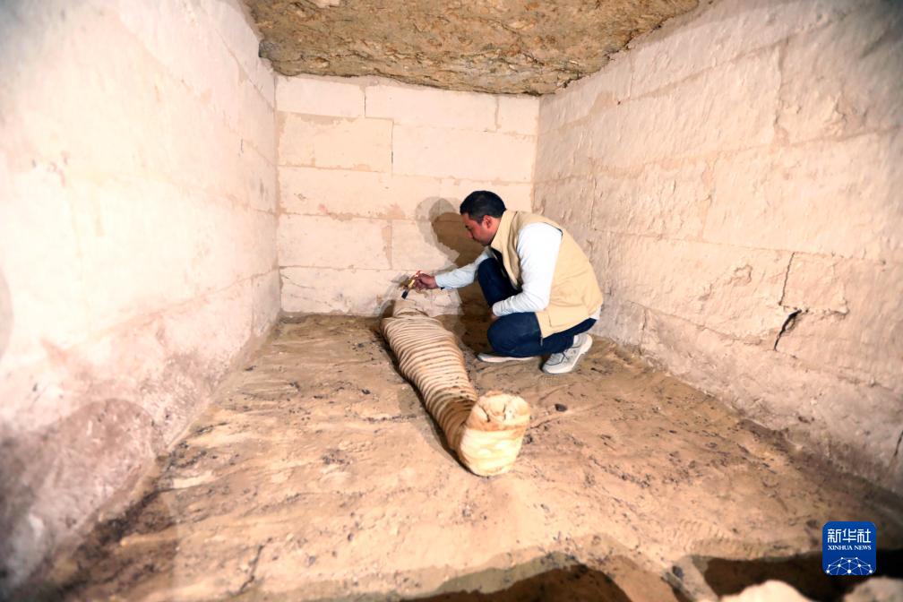 10月15日，在埃及明亞省考古現場，考古人員清理一座石鑿墓中的木乃伊。新華社發(fā)（艾哈邁德·戈馬攝）