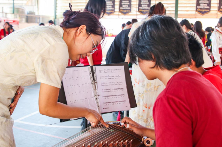 志愿者教師指導學生彈奏古箏?；顒又鬓k方供圖