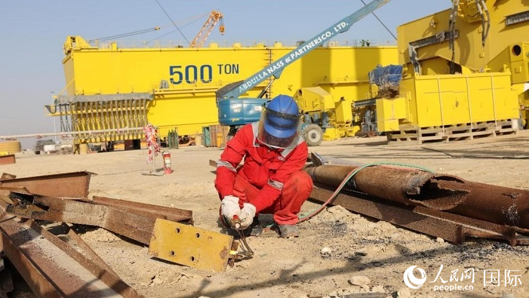 工人正在龍門(mén)吊吊裝現(xiàn)場(chǎng)切割金屬件。人民網(wǎng)記者管克江攝