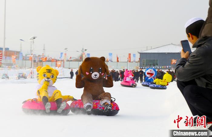 圖為臨夏市南龍鎮(zhèn)馬家莊村舉辦的鄉(xiāng)村文化旅游節(jié)上，游客穿著卡通服裝在體驗(yàn)雪上飛碟項(xiàng)目。近年來，臨夏州形成了“春賞花、夏避暑、秋摘果、冬玩雪”的全季節(jié)旅游產(chǎn)品體系。(資料圖) 高展 攝