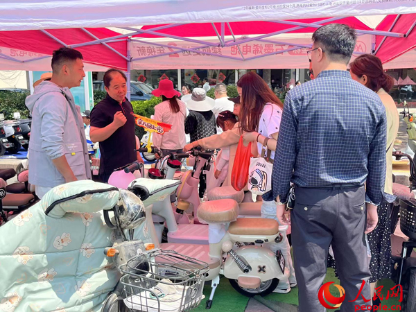 某電動(dòng)自行車品牌工作人員向消費(fèi)者介紹以舊換新相關(guān)情況。人民網(wǎng)記者 杜燕飛攝