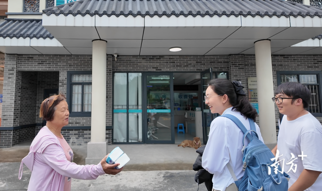 公共服務(wù)組成員王櫻潔（中）和張龍（右）在崖口村衛(wèi)生室前跟村民打招呼。