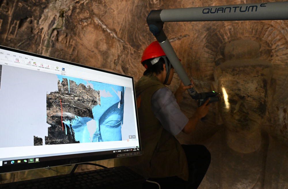 2025年4月9日，武漢大學(xué)文化遺產(chǎn)智能計算實驗室團隊成員在魏字洞使用關(guān)節(jié)臂掃描儀對佛像進行數(shù)字化掃描。圖片來源新華社