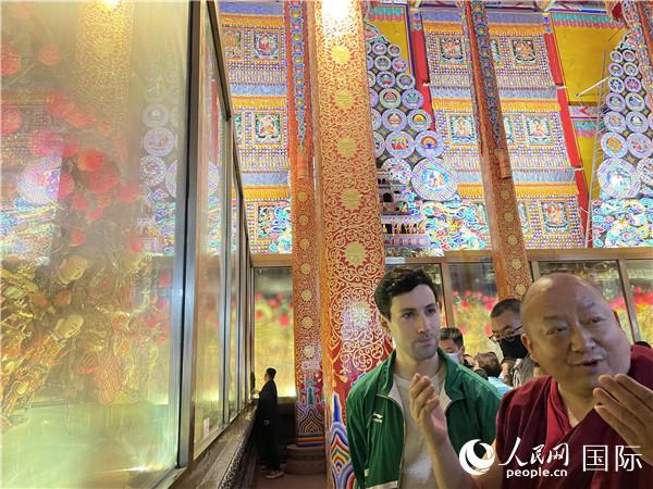 7月25日，省級(jí)非物質(zhì)文化遺產(chǎn)項(xiàng)目塔爾寺酥油花的代表性傳承人朋措堅(jiān)參（右）在塔爾寺酥油花館講解酥油花的制作過(guò)程。人民網(wǎng) 謝瑩攝