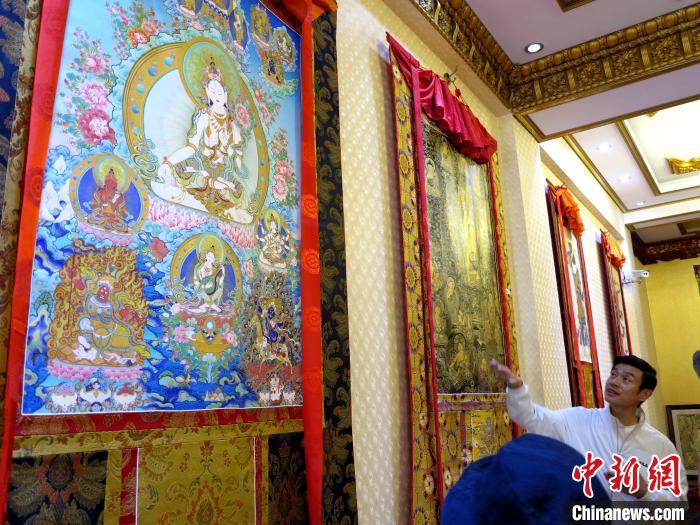 圖為完德尖措展示熱貢龍樹畫苑內(nèi)的唐卡。　張?zhí)砀?攝