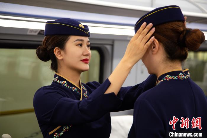 圖為青藏鐵路西格段“復(fù)興號(hào)”動(dòng)車組乘務(wù)員互相整理新制服。　李磊 攝