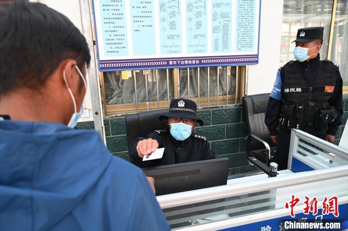 圖為移民管理警察登記完身份信息后將證件歸還給行人?！≮w朗 攝