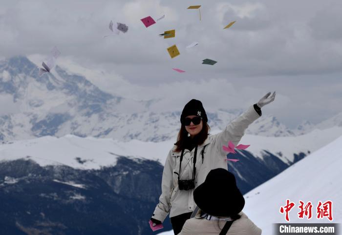 圖為5月14日，游客在西藏林芝色季拉山觀景臺拋灑“隆達”(風馬旗，藏族民眾的一種祈福方式)。　李林 攝