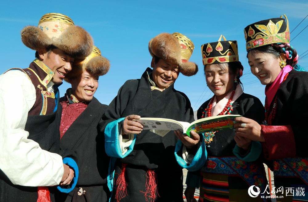 鄉(xiāng)親們身著民族盛裝，圍站在一起認(rèn)真翻看日歷，共話農(nóng)事安排與時(shí)節(jié)規(guī)律，笑容洋溢傳遞豐收期盼。人民網(wǎng)記者 吳雨仁攝