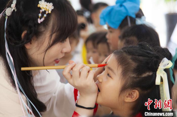 圖為老師在孩子們額頭上點(diǎn)上雄黃，驅(qū)邪辟禍。　董觀生 攝